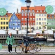Femme senior marchant le long du canal de Nyhavn à Copenhague, maisons colorées et vélos en arrière-plan
