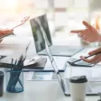 Jeune collaboratrice Zillennial échangeant avec son manager dans un espace de travail moderne, tablette à la main.