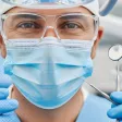 Dentiste portant un masque et des lunettes tenant des outils médicaux