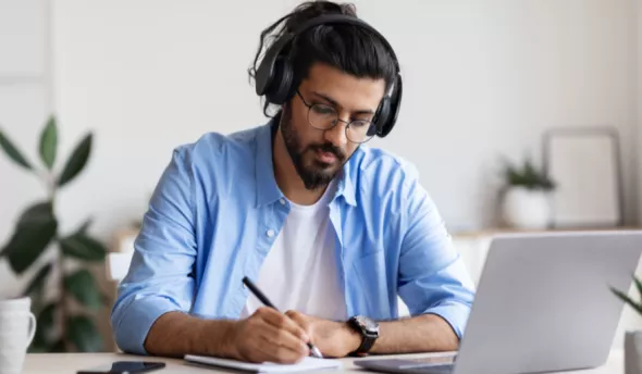un homme avec un casque audio qui écrit