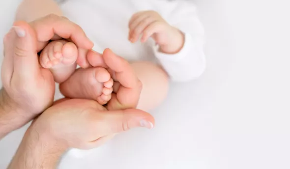 père tenant pieds de son bébé