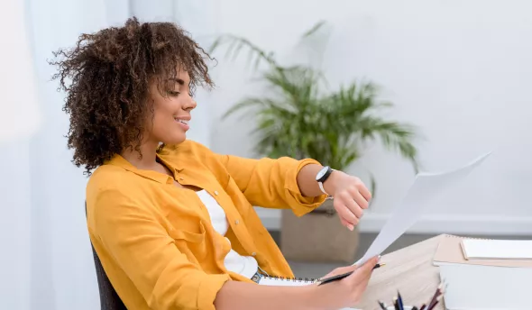 Femme au bureau qui regarde sa montre