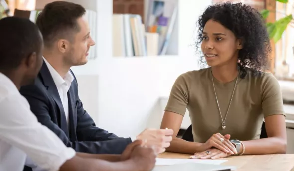 3 personnes en train de discuter autour d'une table