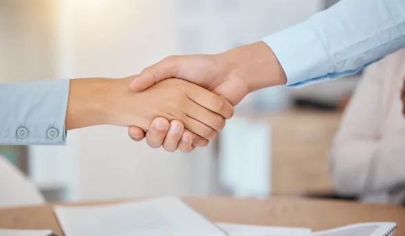 deux personnes se serre la main dans le cadre d'un onboarding ou d'un offboarding
