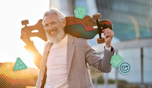 Homme senior souriant portant un skateboard sur l’épaule en tenue professionnelle décontractée