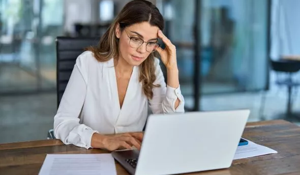 Employé la tête dans les mains devant son ordinateur, illustrant la fatigue extrême du burn-out.