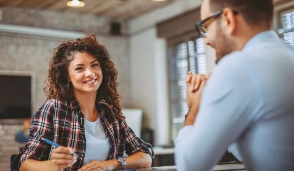 Une responsable RH vérifie sur un tableau les plafonds et planchers d’indemnités liés au licenciement sans cause réelle et sérieuse, pour sécuriser les procédures internes.