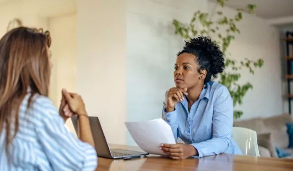 Candidate échangeant avec un recruteur et prenant des notes pour poser ses questions finales.