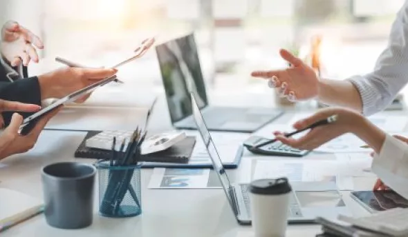 Jeune collaboratrice Zillennial échangeant avec son manager dans un espace de travail moderne, tablette à la main.