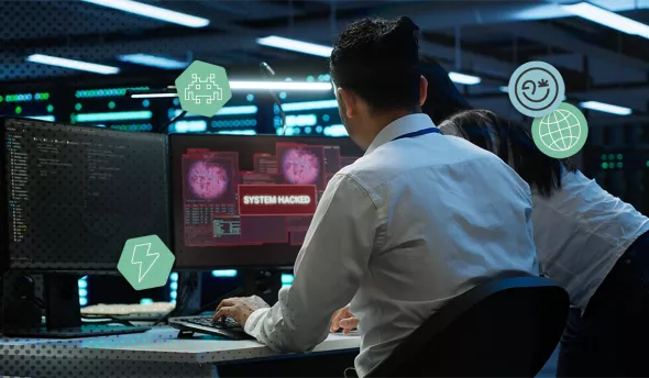 Personnes devant des écrans de PC avec une mention système hacké