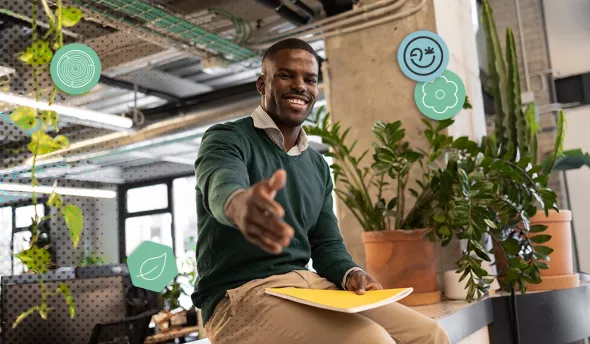 Collaborateur souriant tend la main dans un bureau végétalisé, ambassadeur biodiversité