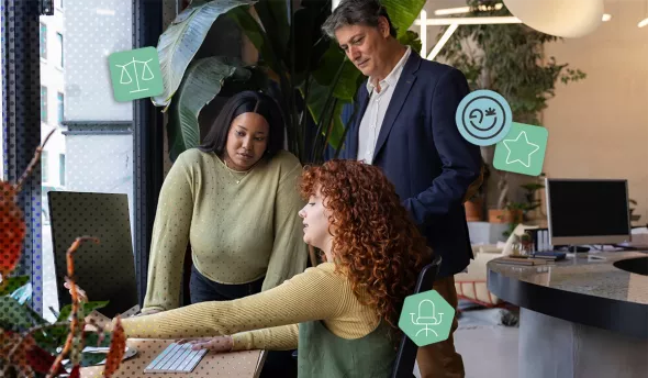 Trois collègues de générations différentes collaborent autour d’un ordinateur au bureau