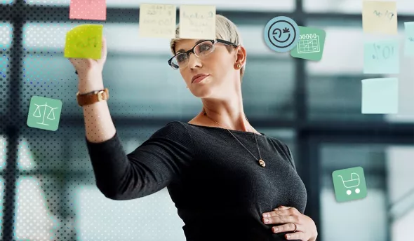 Dirigeante enceinte écrivant des post-it dans un bureau moderne vitré