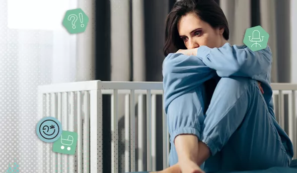 Femme triste et pensive en pyjama bleu assise devant un lit de bébé vide