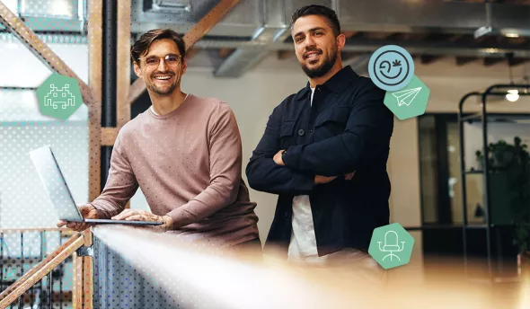 Deux collègues souriants travaillant ensemble dans des bureaux modernes en open space