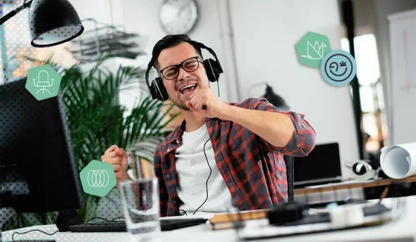 Homme heureux au bureau écoutant de la musique avec un casque et chantant