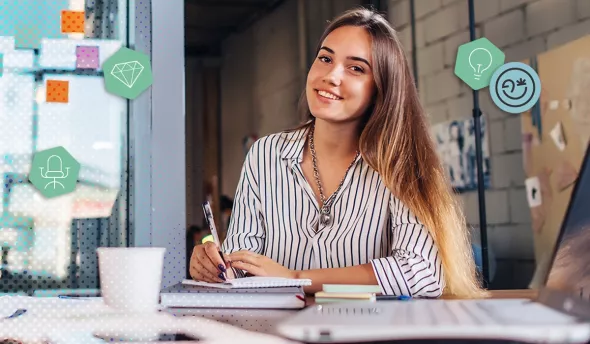 Femme souriante rédigeant des notes sur un carnet, ordinateur et tasse de café à portée de main.
