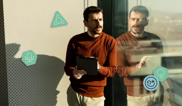 Homme debout près d’une fenêtre, concentré sur sa tablette