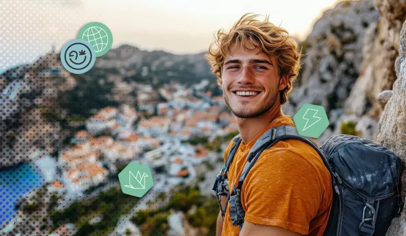 Jeune homme souriant en randonnée, en haut d’un point de vue côtier ensoleillé