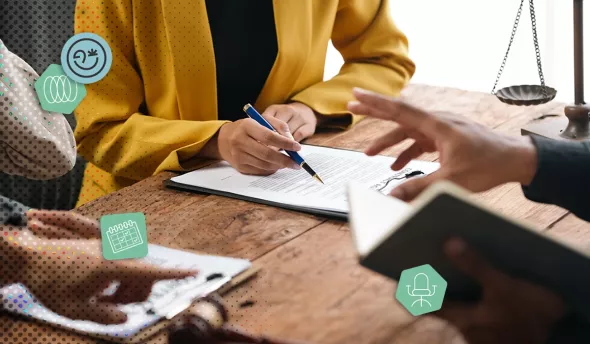 Discussion professionnelle autour d’un contrat sur table en bois, symboles juridiques visibles