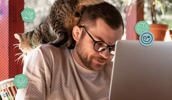 Homme travaillant sur un ordinateur portable avec un chat perché sur son épaule