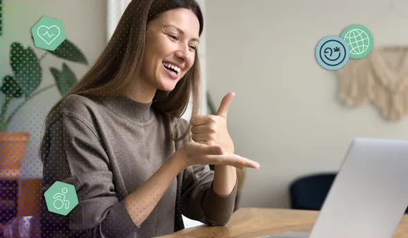 femme souriante utilisant la langue des signes lors d’un échange en visio sur ordinateur