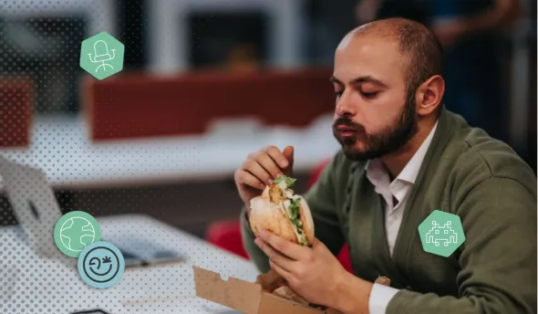 Un homme mange un sandwich au bureau
