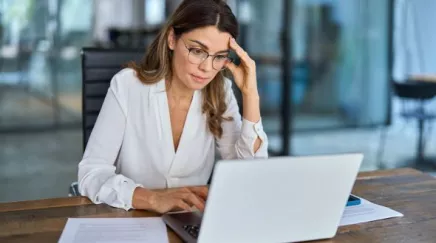 Employé la tête dans les mains devant son ordinateur, illustrant la fatigue extrême du burn-out.