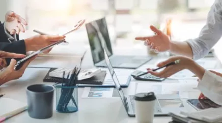 Jeune collaboratrice Zillennial échangeant avec son manager dans un espace de travail moderne, tablette à la main.