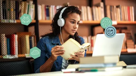 Jeune femme étudiant avec un livre et un ordinateur portable dans une bibliothèque moderne.