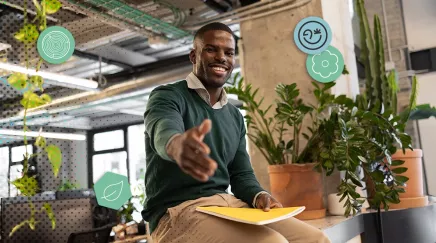 Collaborateur souriant tend la main dans un bureau végétalisé, ambassadeur biodiversité