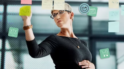 Dirigeante enceinte écrivant des post-it dans un bureau moderne vitré