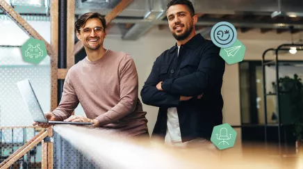 Deux collègues souriants travaillant ensemble dans des bureaux modernes en open space