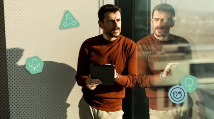 Homme debout près d’une fenêtre, concentré sur sa tablette