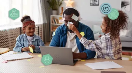 Père en télétravail distrait par ses enfants jouant avec des post-it autour de lui à la maison