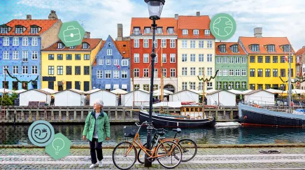 Femme senior marchant le long du canal de Nyhavn à Copenhague, maisons colorées et vélos en arrière-plan