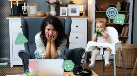 Mère stressée travaillant à domicile avec son bébé assis à côté dans une chaise haute