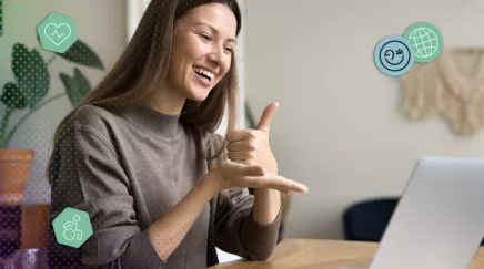 femme souriante utilisant la langue des signes lors d’un échange en visio sur ordinateur