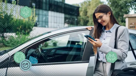 Une femme sort de son véhicule professionnel et regarde son téléphone en souriant